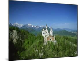 Neuschwanstein Castle on a Wooded Hill with Mountains in the Background, in Bavaria, Germany-null-Mounted Photographic Print