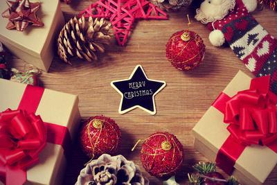 A Pile of Gifts and Christmas Ornaments, such as Christmas Balls and Stars, on a Rustic Wooden Tabl