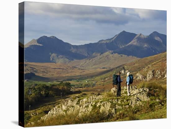 North Wales, Snowdonia; a Man and Woman Stop to Look at their Map Whilst Hiking in Snowdonia;-John Warburton-lee-Stretched Canvas