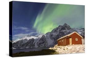 Northern Lights (Aurora Borealis) Illuminate Snowy Peaks and Wooden Cabin on a Starry Night-Roberto Moiola-Stretched Canvas