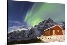 Northern Lights (Aurora Borealis) Illuminate Snowy Peaks and Wooden Cabin on a Starry Night-Roberto Moiola-Stretched Canvas