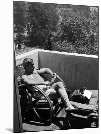 Novelist and Script Writer William Faulkner Reading on His Hotel Balcony-null-Mounted Premium Photographic Print