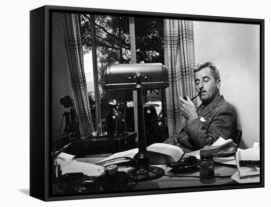 Novelist and Script Writer William Faulkner Smoking a Pipe at His Desk at Warner Brothers Studios-null-Framed Stretched Canvas