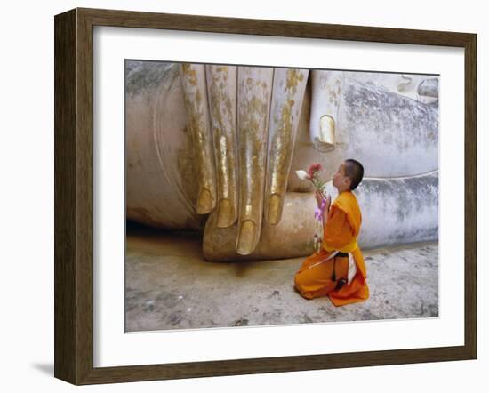 Novice Buddhist Monk Kneeling Beneath the Phra Atchana Buddha Statue, Sukhothai Province, Thailand-Gavin Hellier-Framed Photographic Print