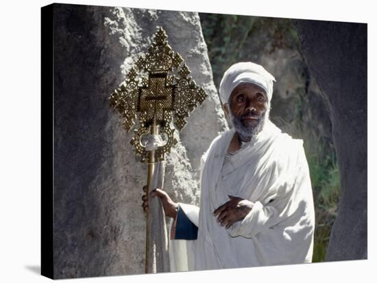 Old Ethiopian Orthodox Priest Holds a Large Brass Coptic Cross at Rock-Hewn Church of Adadi Maryam-Nigel Pavitt-Stretched Canvas