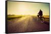 Old Man Riding A Bike On Asphalt Road Towards The Sunny Sunset Sky-Michal Bednarek-Framed Stretched Canvas