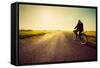 Old Man Riding A Bike On Asphalt Road Towards The Sunny Sunset Sky-Michal Bednarek-Framed Stretched Canvas