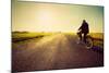 Old Man Riding A Bike On Asphalt Road Towards The Sunny Sunset Sky-Michal Bednarek-Mounted Art Print