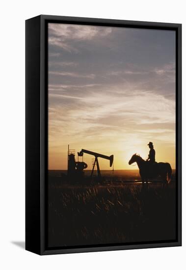 Old West, New West, Man Sitting on Horse with Oil Refinery at Sunset-David R^ Frazier-Framed Stretched Canvas