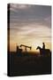 Old West, New West, Man Sitting on Horse with Oil Refinery at Sunset-David R^ Frazier-Stretched Canvas