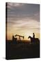 Old West, New West, Man Sitting on Horse with Oil Refinery at Sunset-David R^ Frazier-Stretched Canvas