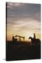 Old West, New West, Man Sitting on Horse with Oil Refinery at Sunset-David R^ Frazier-Stretched Canvas