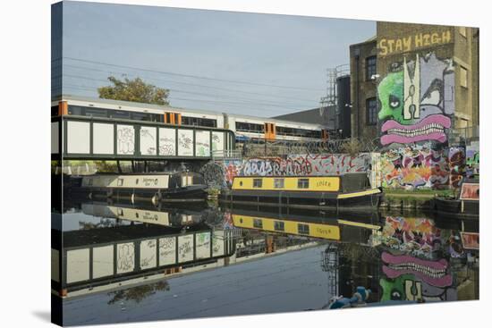 Overground train drives past canal by artists studios and warehouses in Hackney Wick, London, Engla-Julio Etchart-Stretched Canvas