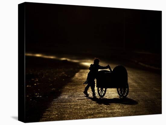 Pakistani Boy Pushes a Cart Along the Main Street in Rawalpindi, Pakistan-null-Stretched Canvas