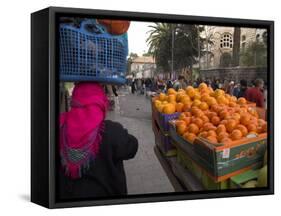 Palestinian Woman in Colourful Scarf and Carrying Bag on Her Head Walking Past an Orange Stall-Eitan Simanor-Framed Stretched Canvas