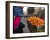 Palestinian Woman in Colourful Scarf and Carrying Bag on Her Head Walking Past an Orange Stall-Eitan Simanor-Framed Photographic Print