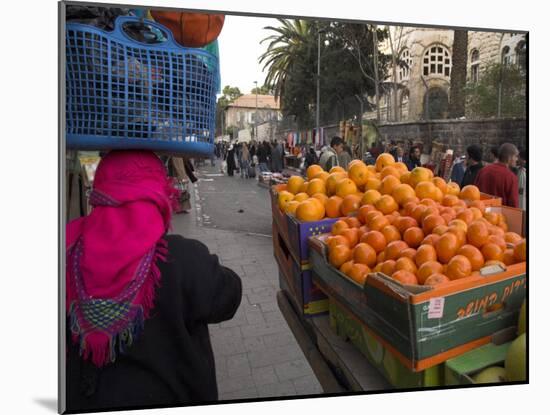 Palestinian Woman in Colourful Scarf and Carrying Bag on Her Head Walking Past an Orange Stall-Eitan Simanor-Mounted Photographic Print