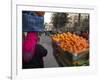 Palestinian Woman in Colourful Scarf and Carrying Bag on Her Head Walking Past an Orange Stall-Eitan Simanor-Framed Photographic Print