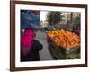 Palestinian Woman in Colourful Scarf and Carrying Bag on Her Head Walking Past an Orange Stall-Eitan Simanor-Framed Photographic Print