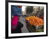 Palestinian Woman in Colourful Scarf and Carrying Bag on Her Head Walking Past an Orange Stall-Eitan Simanor-Framed Photographic Print