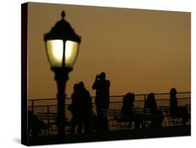 Passengers on a Ferry Pass a Street Lamp on the Waterfront at Battery Park-null-Stretched Canvas