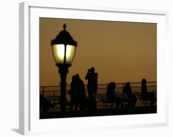 Passengers on a Ferry Pass a Street Lamp on the Waterfront at Battery Park-null-Framed Photographic Print