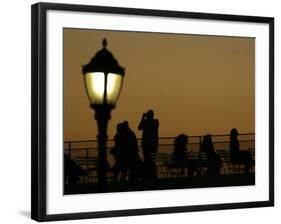 Passengers on a Ferry Pass a Street Lamp on the Waterfront at Battery Park-null-Framed Photographic Print
