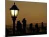 Passengers on a Ferry Pass a Street Lamp on the Waterfront at Battery Park-null-Mounted Photographic Print