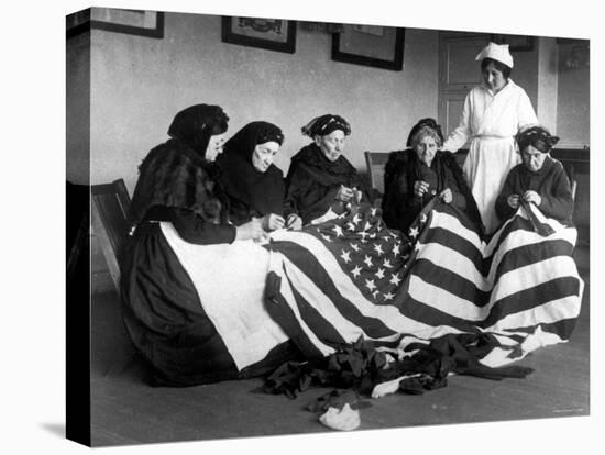 Patriotic Old Female Immigrants Sewing an American Flag under Supervision of Instructor Rose Radin-null-Stretched Canvas