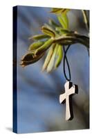 Pendant with cross on a young green chestnut leaf at springtime-null-Stretched Canvas