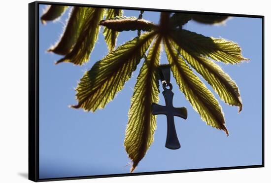 Pendant with cross on a young green chestnut leaf at springtime-null-Framed Stretched Canvas