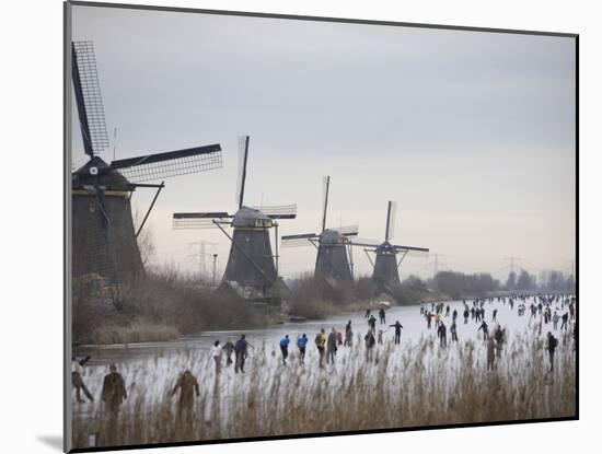 People Skate on Frozen Canals in Kinderdijk's Mill Area, a UNESCO World Heritage Site, Netherlands-null-Mounted Photographic Print