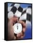 Person's Hand Holding a Stopwatch in Front of a Checkered Flag-null-Framed Stretched Canvas