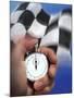 Person's Hand Holding a Stopwatch in Front of a Checkered Flag-null-Mounted Photographic Print