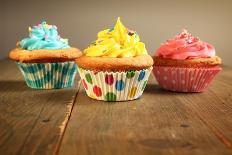 Three Different Colors Cupcakes On A Wooden Table, Blue, Yellow And Pink-pink candy-Art Print