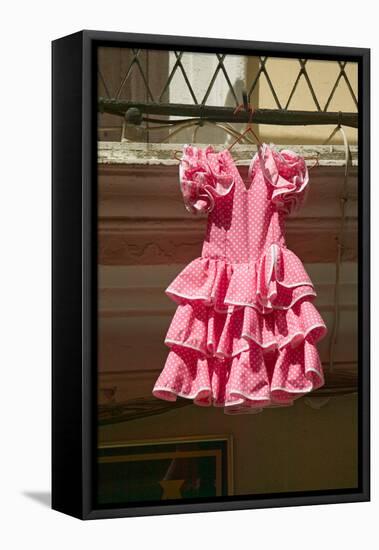 Pink flamenco dress for little girl hangs in Centro old district of Sevilla Spain-null-Framed Stretched Canvas