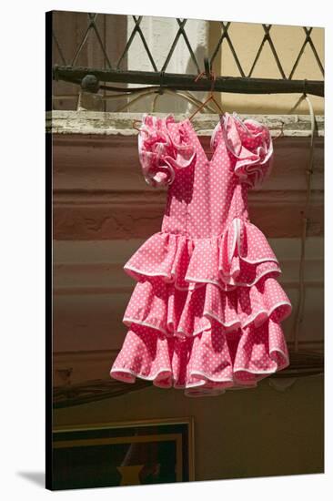 Pink flamenco dress for little girl hangs in Centro old district of Sevilla Spain-null-Stretched Canvas