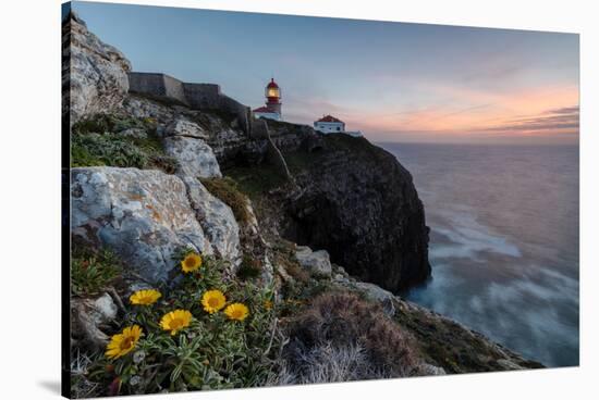 Pink sky at sunset and yellow flowers frame the lighthouse, Cabo De Sao Vicente, Sagres, Algarve, P-Roberto Moiola-Stretched Canvas