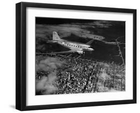 Plane Flying over a City from a Story Concerning United Airlines-Carl Mydans-Framed Photographic Print