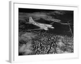 Plane Flying over a City from a Story Concerning United Airlines-Carl Mydans-Framed Photographic Print