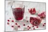 Pomegranate Pieces and a Glass of Pomegranate Juice on White Wooden Table-Jana Ihle-Mounted Photographic Print