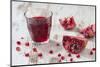 Pomegranate Pieces and a Glass of Pomegranate Juice on White Wooden Table-Jana Ihle-Mounted Photographic Print