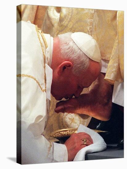 Pope John Paul II Kisses the Foot of a Clergyman-null-Stretched Canvas
