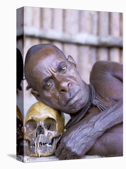 Portrait of an Asmat Tribesman Leaning on a Human Skull, Irian Jaya, Indonesia-Claire Leimbach-Stretched Canvas