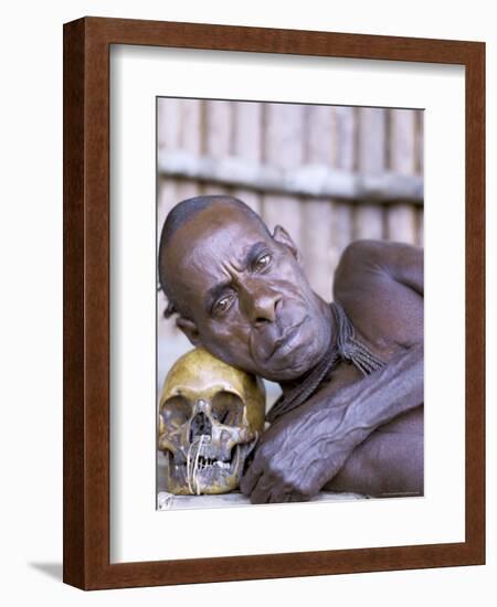 Portrait of an Asmat Tribesman Leaning on a Human Skull, Irian Jaya, Indonesia-Claire Leimbach-Framed Photographic Print