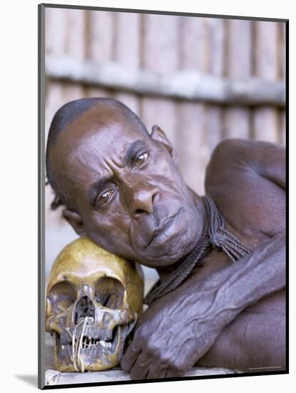 Portrait of an Asmat Tribesman Leaning on a Human Skull, Irian Jaya, Indonesia-Claire Leimbach-Mounted Photographic Print