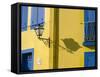 Portugal, Aveiro. Shadow of street lantern on colorful yellow building with bright blue shutters.-Julie Eggers-Framed Stretched Canvas