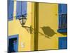 Portugal, Aveiro. Shadow of street lantern on colorful yellow building with bright blue shutters.-Julie Eggers-Mounted Photographic Print