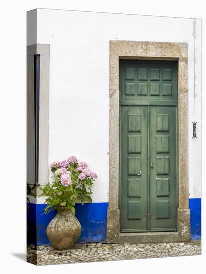 Portugal, Obidos. Pink hydrangea in terracotta pot next to a green door.-Julie Eggers-Stretched Canvas