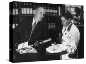 Pouring Champagne from a Huge Tilted Toward Glass Held on Tray by Waiter, at the Hotel Hilton-Ralph Crane-Stretched Canvas